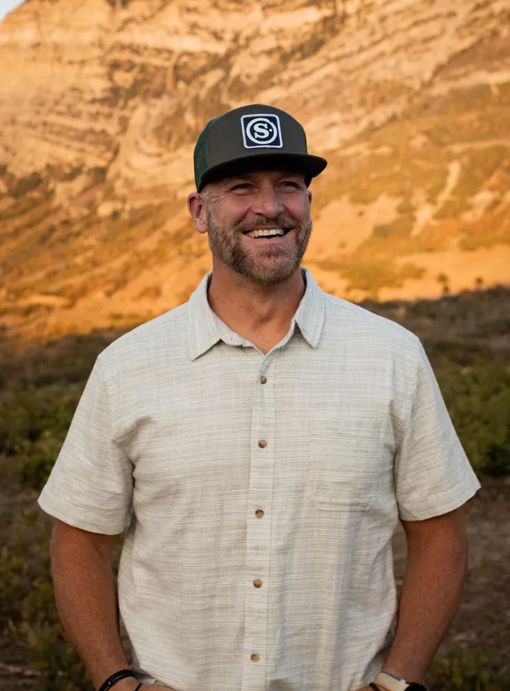 James Lewis smiling outdoors in the mountains